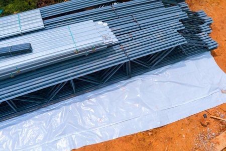 Steel construction materials are organized on ground at building site during works day