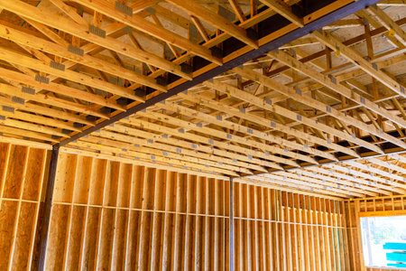 Wooden beams trusses support ceiling in an unfinished residential construction site on work day.