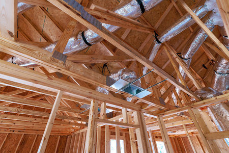 New residential construction showcases wooden beams ductwork being installed in new home setting.の写真素材