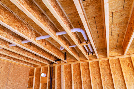 Interior structure wooden beams plumbing pipes in new home construction project during works daytime.の写真素材