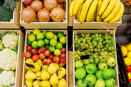 Vibrant display of various fruits, vegetables arranged neatly in crates at busy market.の写真素材