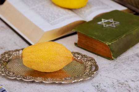 Religious traditional Jewish holiday for Sukkot celebration, etrog citrus fruit, prayer book with...