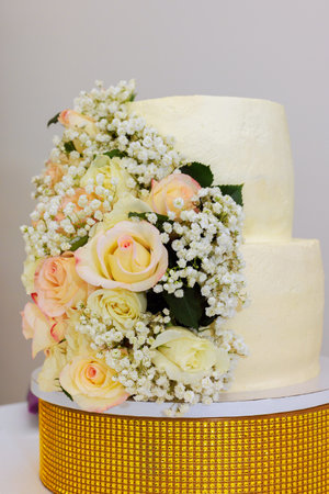 Beautifully decorated two tier cake features delicate roses babys breath, perfect for festive...