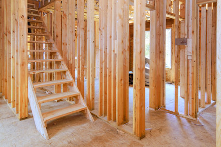 Wooden framing in residential construction site reveals staircase an open layout ready for further...