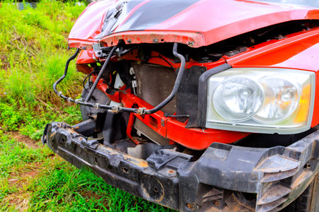 Truck with significant front end damage sits in green field, showcasing wrecked bumper, exposed...