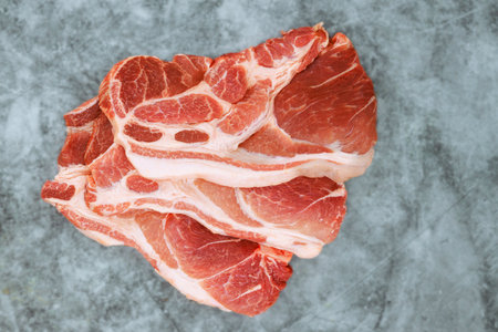 Several thick pork chops laid out on textured gray surface perfect for grilling frying.の写真素材