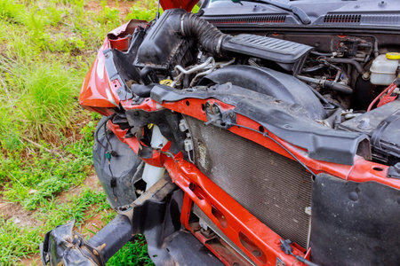 Red car has significant front end damage, with engine components ready insurance claim