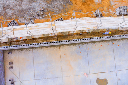 Construction workers build foundation with blocks scaffolding at site under works day