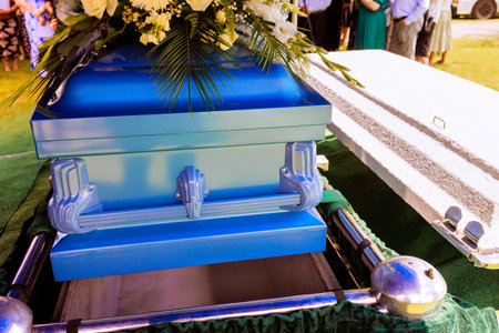 Family, friends gather to pay their respects as casket is lowered during an emotional farewell ceremony.の写真素材