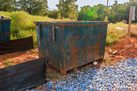 Rusty dumpster located in construction site, surrounded by rocks reflecting works day.