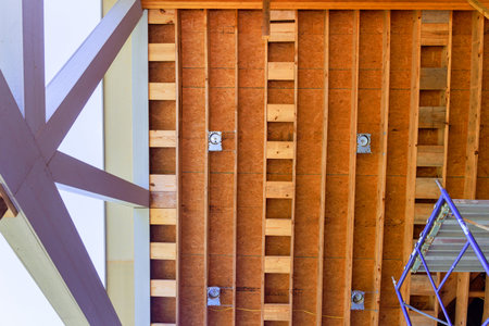 Workers are renovating an interior space, revealing wooden ceiling structure beams supports frame...