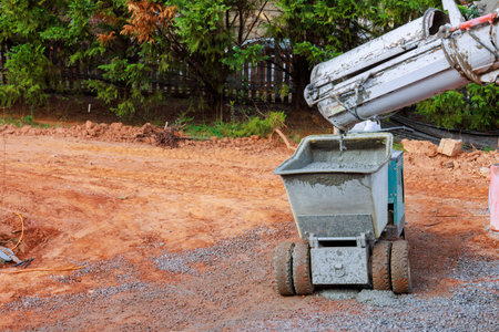 Concrete mixer pours new cement into dumper wheelbarrow buggy truck on construction site
