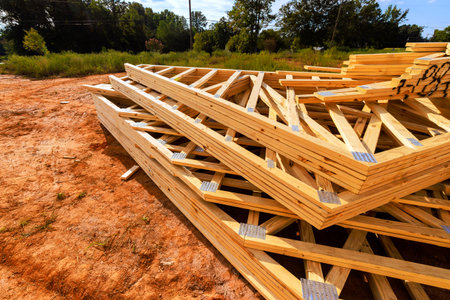 Stacked wooden beams roofing joints are placed on construction site under works day with trees in...