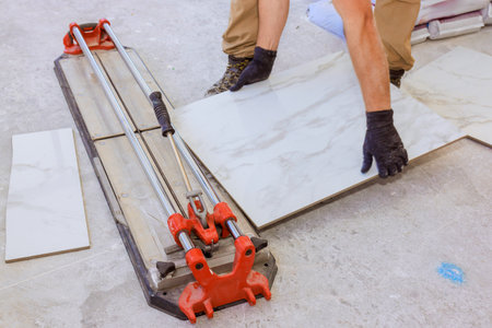 Worker using tile cutter to shape marble tiles on construction site