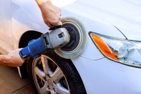 Service man using buffer to polish surface of white car in enhancing its shine appearance.の写真素材