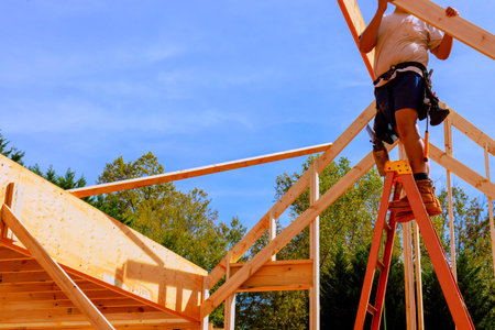 Construction worker stands on ladder, building roof frame under assembly new home