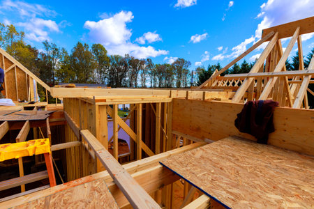 Workers are constructing wooden frame of new house, with joist installation on roof