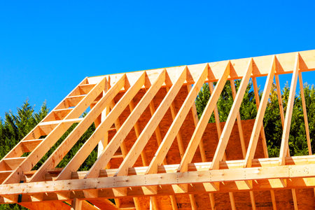Workers build wooden frame for roof truss under beams joist studs