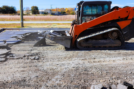 Heavy machinery is breaking up old asphalt in construction site under demolition asphalt