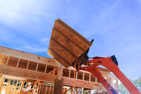 Heavy machinery lifts wooden osb panels for construction under assembly new home