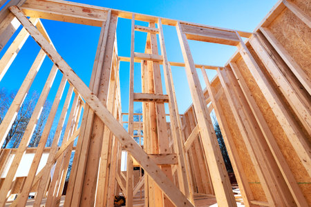 Workers build wooden house beams framework with open walls under construction progress.