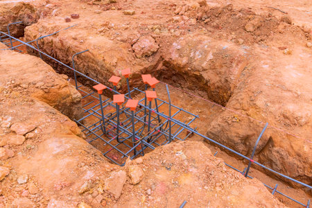 Workers prepare rebar structure in ground for upcoming concrete pour at construction site.