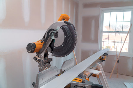 Circular saw is set up on workbench as it cuts through wood room is under renovation with bare walls plentyの写真素材