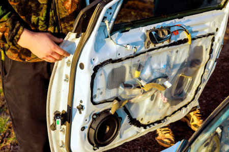 Worker is taking apart car door to fix replace parts in garage serviceの写真素材