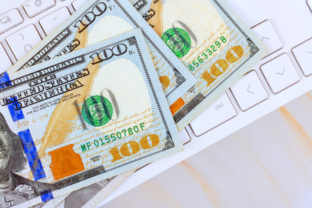 One hundred US dollar cash on laptop keyboard, connection between money online payments