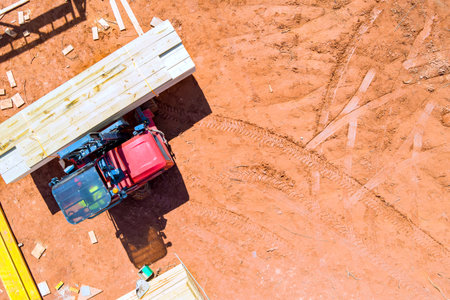Tractor is transporting wooden planks at construction site scattered acrossの写真素材