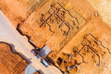 Workers are prepared laying foundation frame of homes in developing area trucks tools are nearby.の写真素材