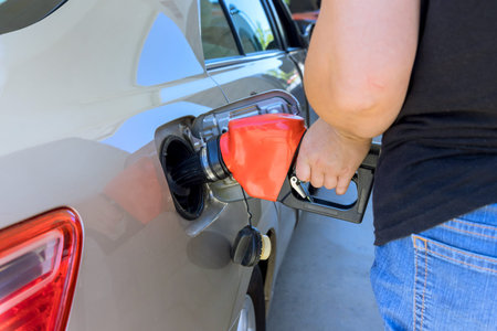 Service worker is filling their car with gas at fuel station in action of refueling.