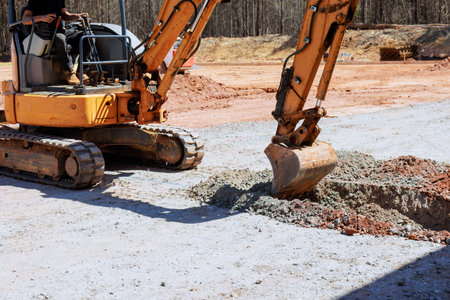 Worker operates an excavator to dig trench at construction site
