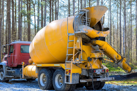 Cement mixer truck is parked in forest area, preparing to mix deliver concrete for construction work.の写真素材