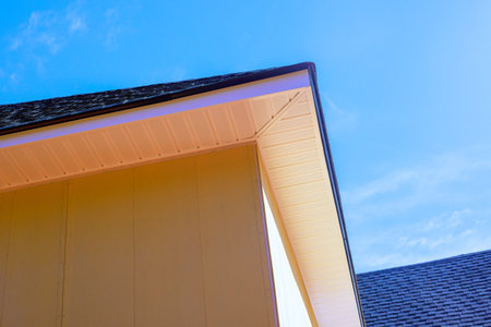 House corner is under installing fiber siding with roof structure highlighting building work design.