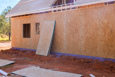 Workers are laying down wood plywood panels for house under construction during build process