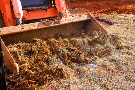 Heavy machinery works to move dirt debris in rural location during landscaping work with soil grass...