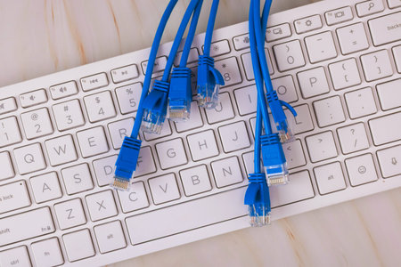 Several blue network cables are on white keyboard in online digital business workspace.