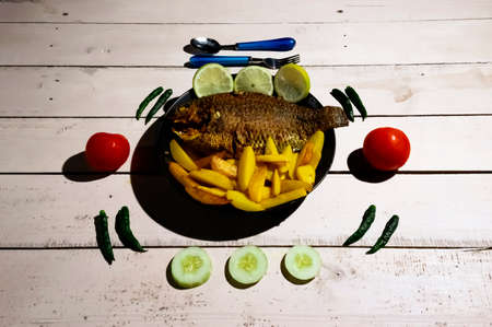 Delicious fried tilapia fish with spicy  chili pepper and tomatoes wood backgroundの写真素材