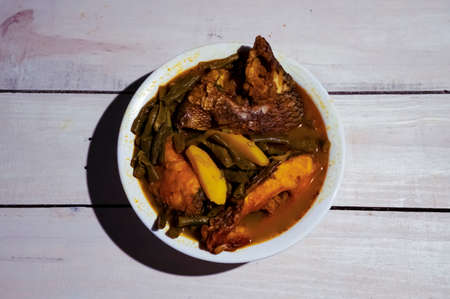 Delicious tilapia fish curry with white plate. Wood background