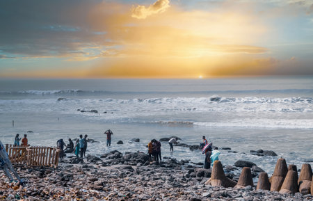 Some people are having fun on the beach, taking pictures, the sun is setting.の写真素材