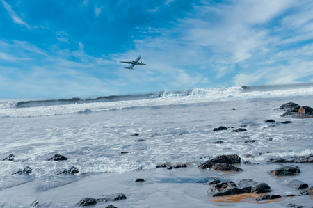 Rocks on the seashore, big waves, airplanes flying in the sky.の写真素材