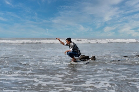 A man is having fun with sea water, big waves are seen, natural beautyの写真素材