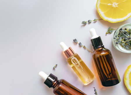 Essential oil in glass bottles with lemon and herbs on white backgroundの素材