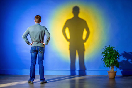 Man looking at the shadow of a man in front of a wallの素材