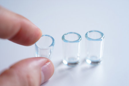 Clear glass cylinders display. Hand placing one in minimalist scientific equipment viewの素材