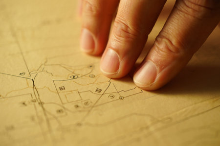 Hand pointing at building sketch on paper map. Fingers on route planning.の素材