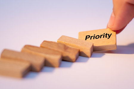 Hand stacking wood blocks with priority. Importance concept. Close up studio shot.の素材