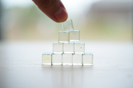 Cubes pyramid. Top layer. Wooden table. Business success. Achieving stability.の素材