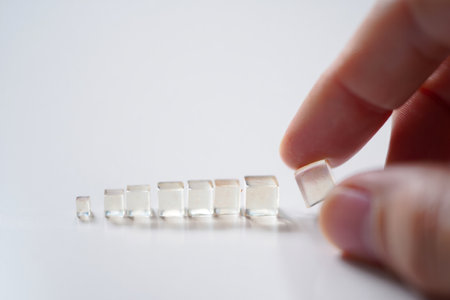 Hand arranging blocks. Clear glass. Scaling growth. Organization.の素材